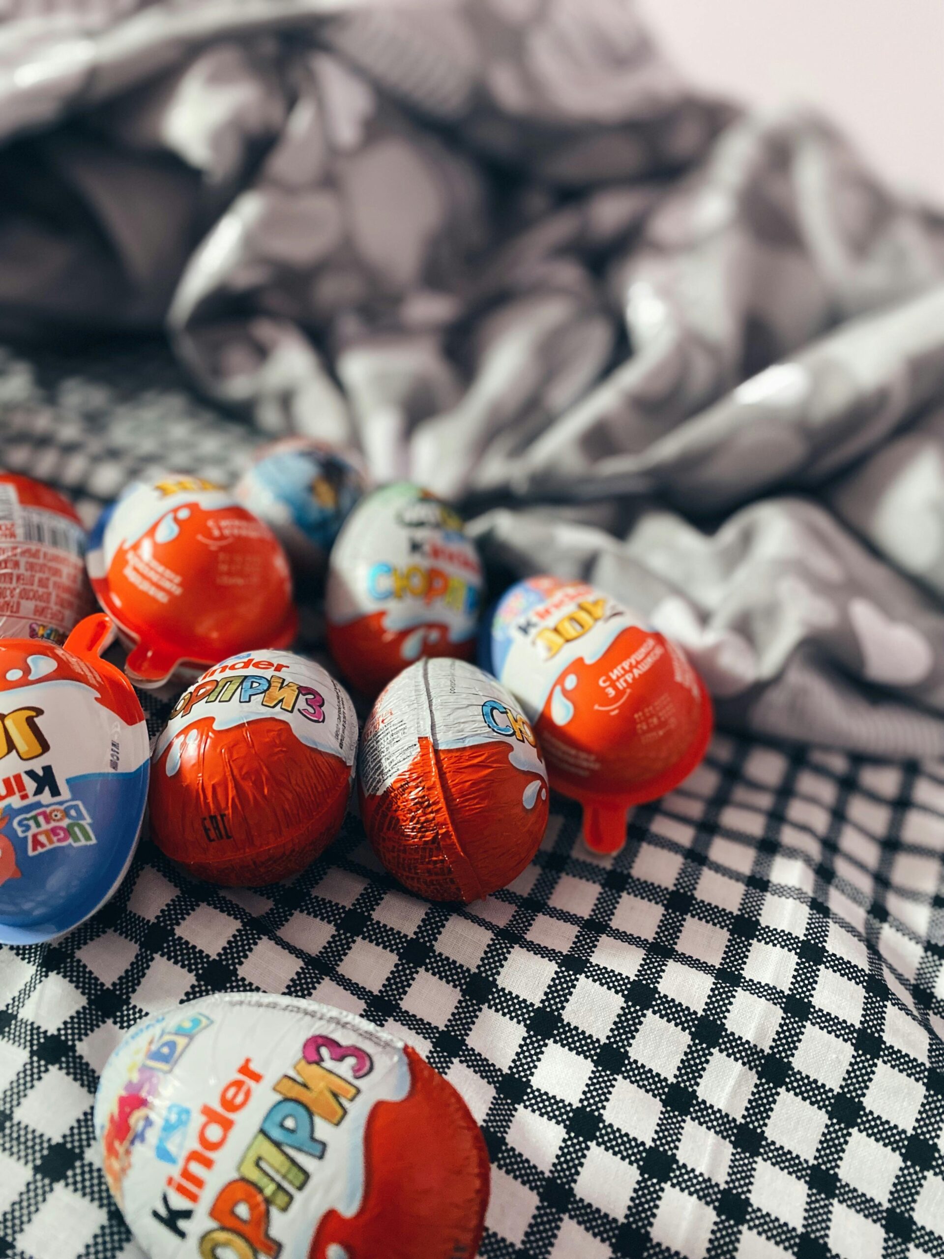 A collection of Kinder chocolate eggs on a textured blanket, perfect for festive treats or gifts.